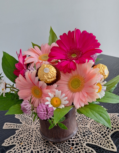 A stunning floral arrangement featuring pink and white roses, complemented by white orchids and lush greenery, beautifully displayed in a white vase.