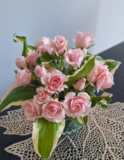 A graceful arrangement of white lilies, accented with green foliage, displayed in a tall, clear glass vase.