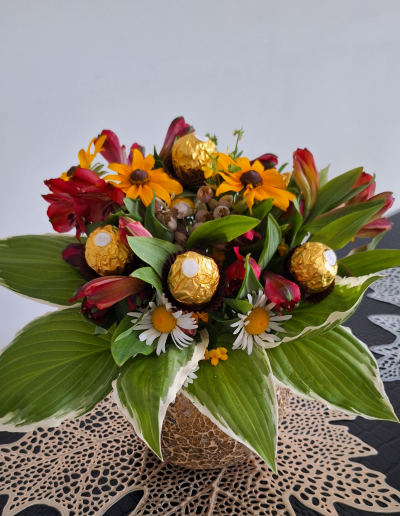 An elegant floral arrangement featuring white roses and green foliage, arranged in a stylish white ceramic pot.