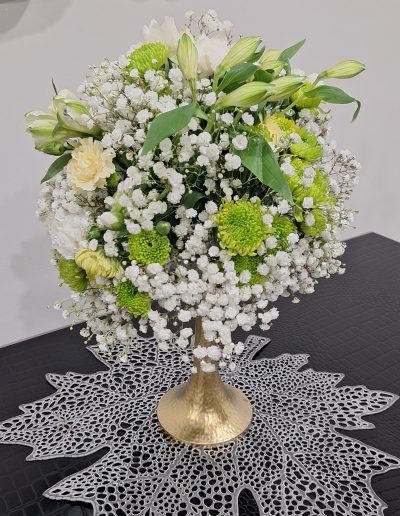 White and green floral arrangement with baby's breath and green chrysanthemums on a gold stand