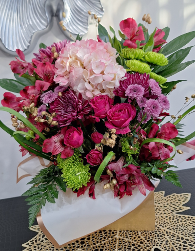 Pink and magenta floral box arrangement with hydrangea and roses.