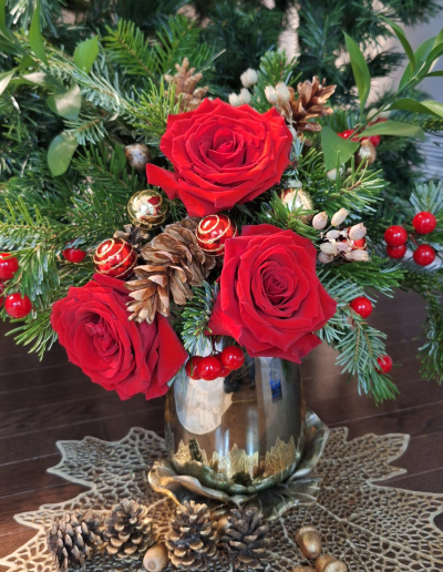 Close-up of red roses with pinecones, ornaments, and evergreen foliage