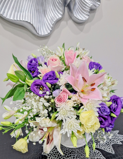 Elegant flower arrangement with pink lilies, roses, purple lisianthus, white chrysanthemums, and baby's breath.